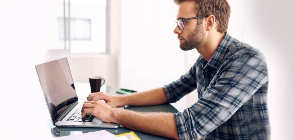 blond, male software developer coding on his laptop